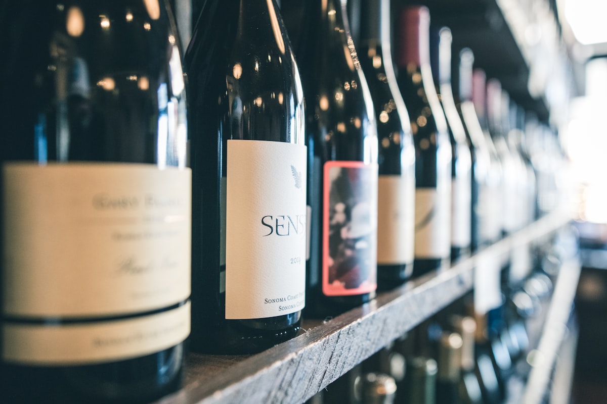 A row of diverse wine bottles on a wooden shelf representing the variety of wine styles